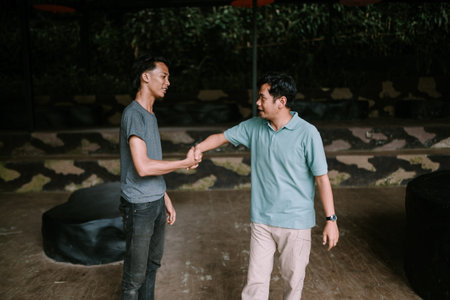 Two men shaking hands in a relaxed outdoor setting, suggesting themes of togetherness and casual leisure.の写真素材