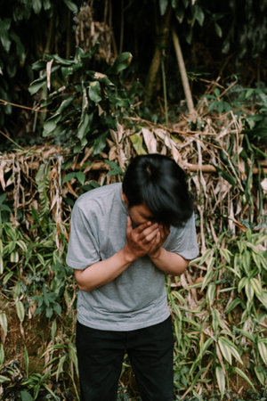 Southeast Asian man caught in mid-sneeze, with a sudden and expressive reaction. Ideal for themes of...