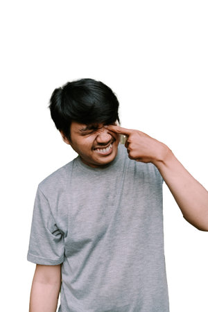 Southeast Asian man rubbing his eyes, appearing tired or sleepy. Ideal for themes of fatigue, waking up, or moments of exhaustionの写真素材