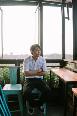 A Southeast Asian man sitting on a chair with his arms crossed, displaying a calm and composed expressionの写真素材
