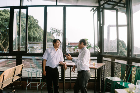 Two Southeast Asian men engaging in an enthusiastic conversation about their work.の写真素材