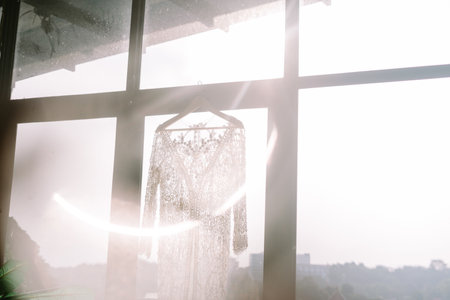 A wedding gown elegantly hung on a window, creating a unique and picturesque indoor settingの写真素材