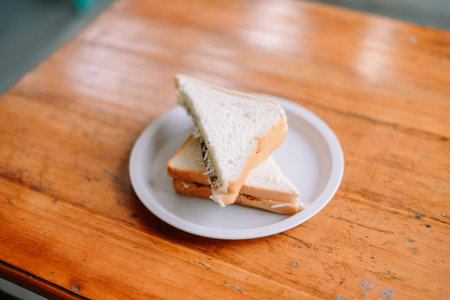 A hand offers a plate with a delicious sandwich.の写真素材