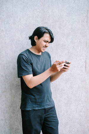 Young man experiencing frustration while playing a mobile game.の写真素材