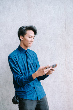 Young man engrossed in playing a mobile game, focused expression.の写真素材
