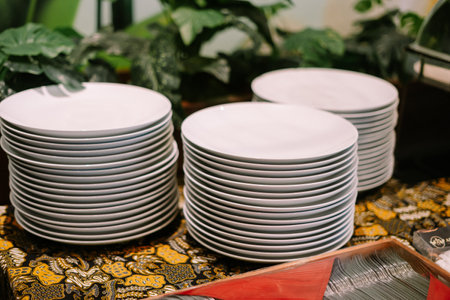 Stacks of clean white plates ready for a catered event.の写真素材