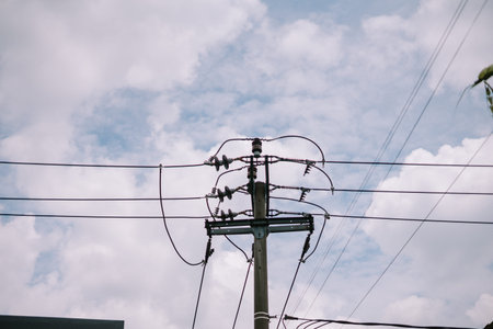 Electricity pylon and power lines silhouetted against a cloudy sky.