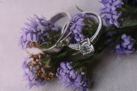 Elegant silver wedding rings nestled amongst delicate purple flowers. A symbol of love and commitment.の写真素材