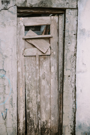 Broken, weathered wooden door in a crumbling concrete wall.の写真素材