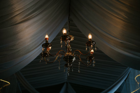 Elegant chandelier hanging from a draped ceiling.の写真素材
