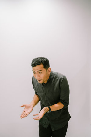 Surprised man with open hands and a shocked expression, reacting to unexpected news.の写真素材