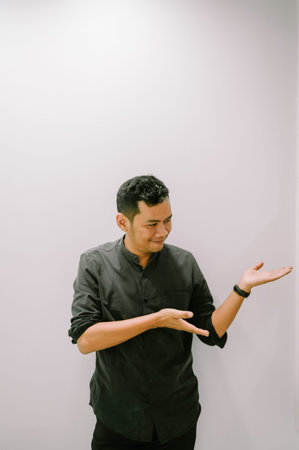 A young man gestures with his hand, presenting or showing something.