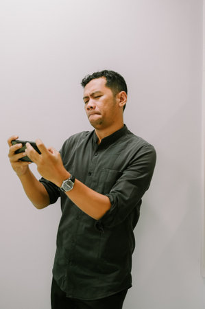 A young man engrossed in a mobile game, enjoying his leisure time.の写真素材