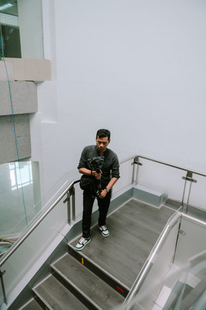 Male photographer ascending modern staircase, camera in hand.
