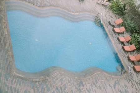 Overhead view of a swimming pool, surrounded by lounge chairs. Captures a serene and inviting...