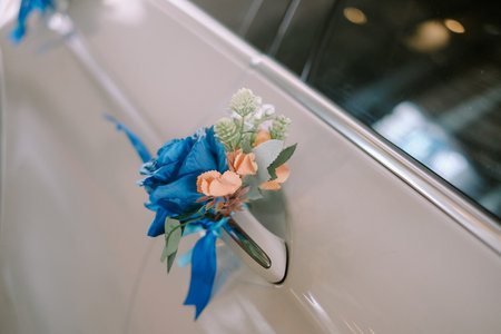 Close-up shot of a decorated vintage car's door handle, adorned with fresh floral arrangement. This festive touch adds elegance to a wedding or special occasion.の写真素材