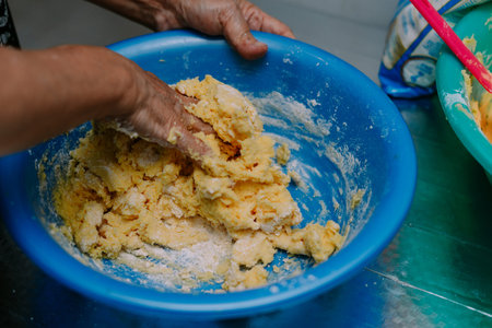 Close up shot of hands mixing dough in a blue bowl. Woman preparing dough in her kitchen at home....