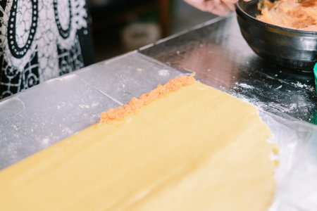 Close-up on the pasta sheet being filled with salmon paste, delicious dish in the making. The fresh...