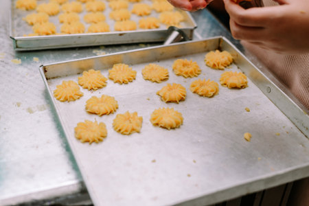 Close up of uncooked butter cookies being arranged on baking sheets, ready for the oven. The homemade cookies showcase the preparation and culinary process of confectioneryの写真素材