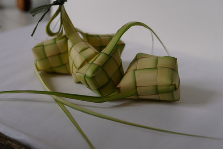 Close-up of ketupat, a diamond-shaped rice cake wrapped in woven young coconut leaves. A traditional culinary dish served during Eid al-Fitr and other celebrations in Indonesia, Malaysia and Southeast Asia. Selective focus.の写真素材