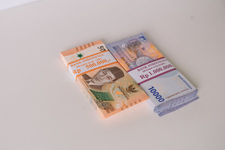 Close-up shot of neatly stacked Indonesian Rupiah banknotes on a clean white background. Illustrates finance, wealth, economy, and investment concepts in Indonesia.の写真素材
