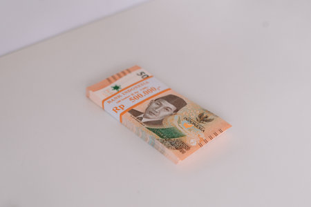 A stack of Indonesian Rupiah banknotes bound together. The orange colored currency is sitting on a white surface. Representing finance, wealth, and the Indonesian economy.の写真素材