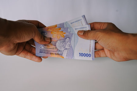 A close-up of hands handling Indonesian Rupiah banknotes. Demonstrates financial transaction, currency exchange, or payment. Represents business, investment, and the Indonesian economy.の写真素材