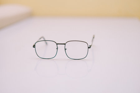 A set of minimalist eyeglasses resting on a clean, light-colored surface. The thin, dark frames and clear lenses project a sense of modern elegance and refined style. Suitable for representing vision correction, intellectual pursuits, or simple sophistication.の写真素材