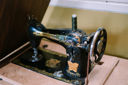 Close-up shot of an antique sewing machine, showcasing its intricate details and decorative...