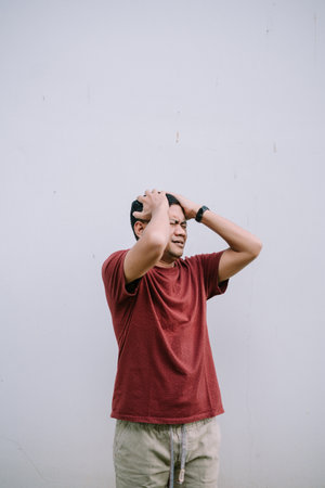 Worried man holding his head. Portrait of an adult expressing stress and anxiety.の写真素材