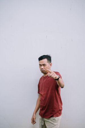 Stern asian man pointing finger to the camera with angry expression. Focus on his serious gaze.