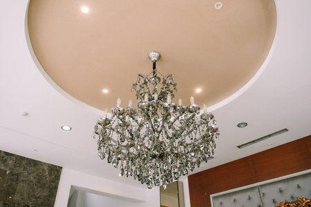 An elegant crystal chandelier provides illumination in a modern designed interior, hanging from the...