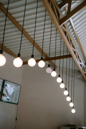 String of lights with bulbs hanging from a roof in a modern building. Decorative interior lighting with modern design.の写真素材