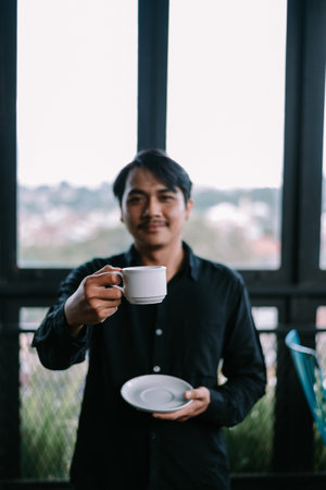 A man offers a coffee mug, creating a feeling of sharing and hospitality. Enjoy a calm morningの写真素材