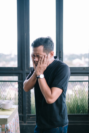 Anxious man covering his face with his hands. A portrait of stress and emotional burnout, conveying worry and sadness.の写真素材