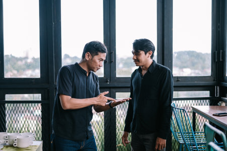 Two men discuss a serious topic in a cafe, showcasing communication and collaboration in modern workspaceの写真素材