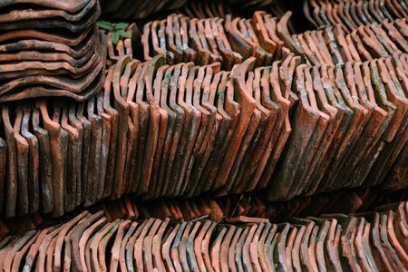 Pile of weathered terracotta roof tiles. Ready for use in building restoration or new roofing projects. Close-up view.の写真素材