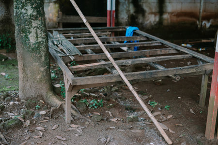 Rustic wooden frame leans by a tree, embodying decay in a forgotten, nature-infused setting. Its aged texture creates a textured background of rural disrepair.の写真素材