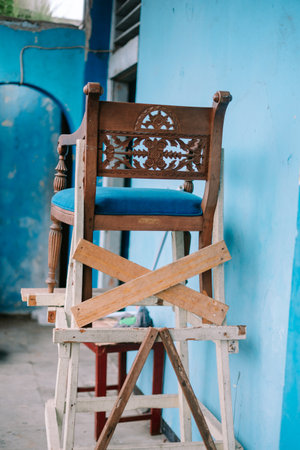 Restoration process of an antique wooden chair with blue velvet seat in workshop. Concept of furniture renovation and craftsmanshipの写真素材