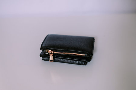 Sleek black leather wallet featuring a gold zipper, perfect for personal finance or business...