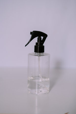 Simple still life of a clear spray bottle with a black nozzle. Ideal for beauty, cleaning, or medical concepts. Minimalist and clean designの写真素材