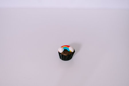 Rainbow decorated cupcake on a plain backdrop, perfect for birthday celebration or creative treatの写真素材