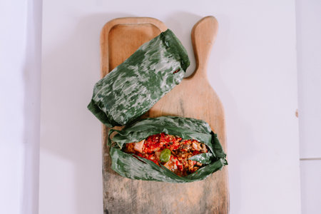 Traditional food wrapped in banana leaves served on a cutting board. Selective focus.