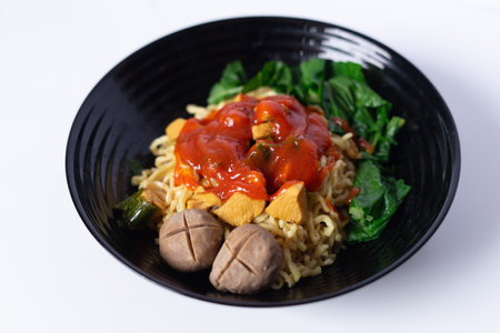 Indonesian Mie Ayam with Bakso served on black bowl, a traditional cuisine from Indonesia. Asian noodles with meatballs, chicken, and fresh vegetables.の写真素材