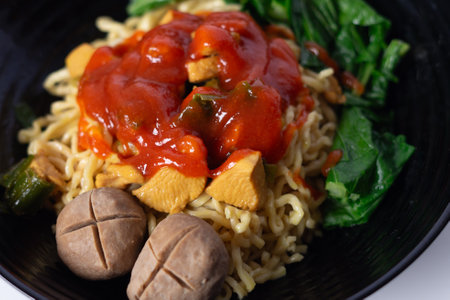 Close-up shot of delicious Mie Ayam. Indonesian noodle dish with chicken, meatballs, and bok choy in a black bowl. Perfect for illustrating diverse cuisine or healthy eatingの写真素材