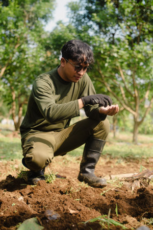 A peanut farmer placing peanut seeds into the soil by hand during the planting process. Traditional farming activity in rural agriculture.の写真素材