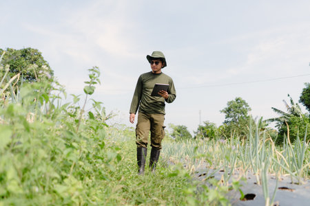 A plant researcher inspecting crop development while holding a tablet, using digital tools to collect data and monitor agricultural progress in the fieldの写真素材