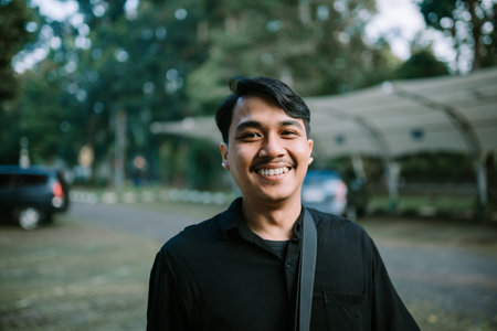 A smiling young man portrait, radiating joy and confidence in an outdoor settingの写真素材