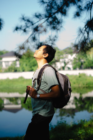 A man takes a deep breath of fresh air as he arrives at a beautiful lake during his travel, enjoying the peaceful and refreshing nature around him.の写真素材
