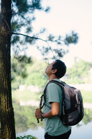A man takes a deep breath of fresh air as he arrives at a beautiful lake during his travel, enjoying...